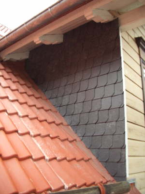 Schieferbekleidete Wand neben einem Ziegeldach