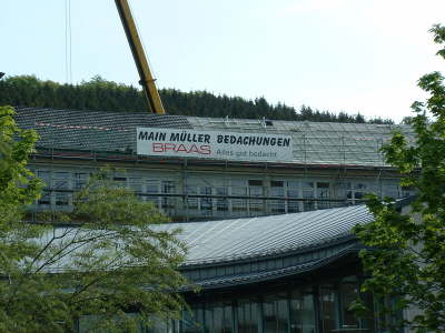 Dacharbeiten an einem Gebäude, Banner der Firma am Gerüst